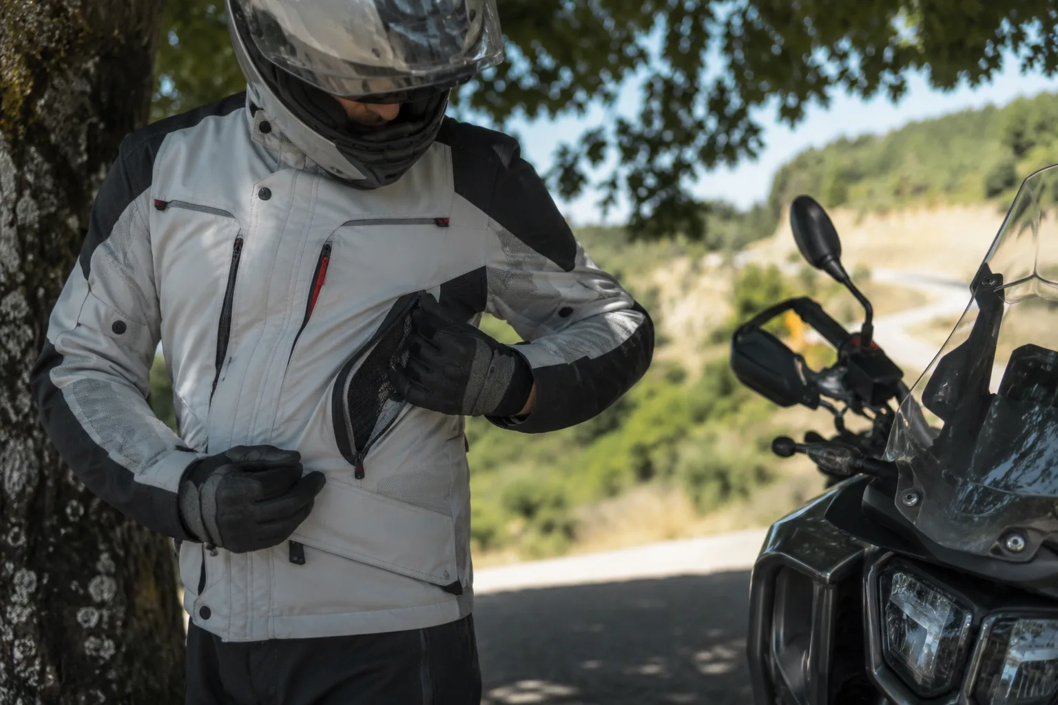Motorradfahrer passt im Schatten die Belüftung seiner Schutzjacke an.