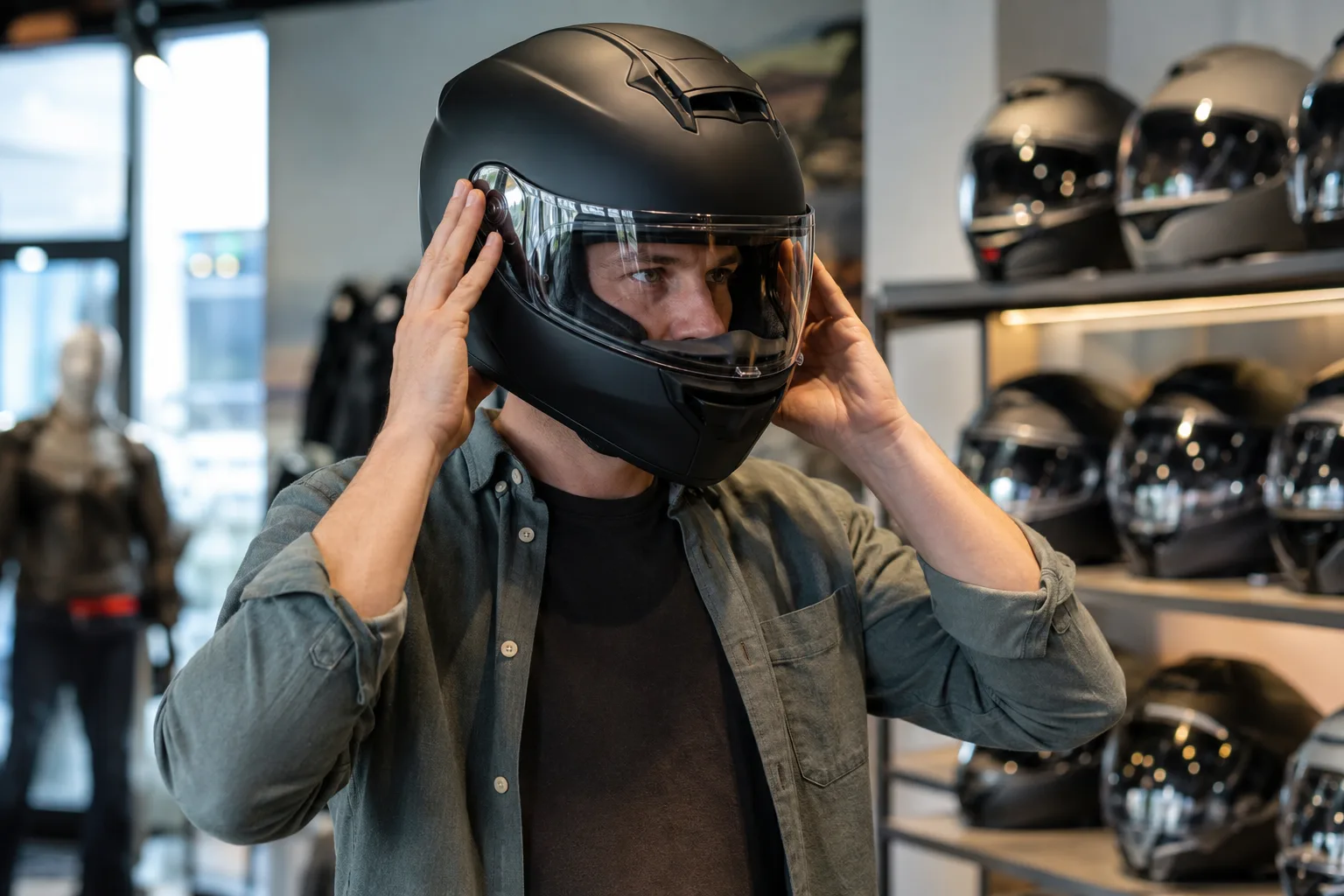 Motorradfahrerin prüft beim Anprobieren eines Integralhelms dessen seitlichen Sitz.